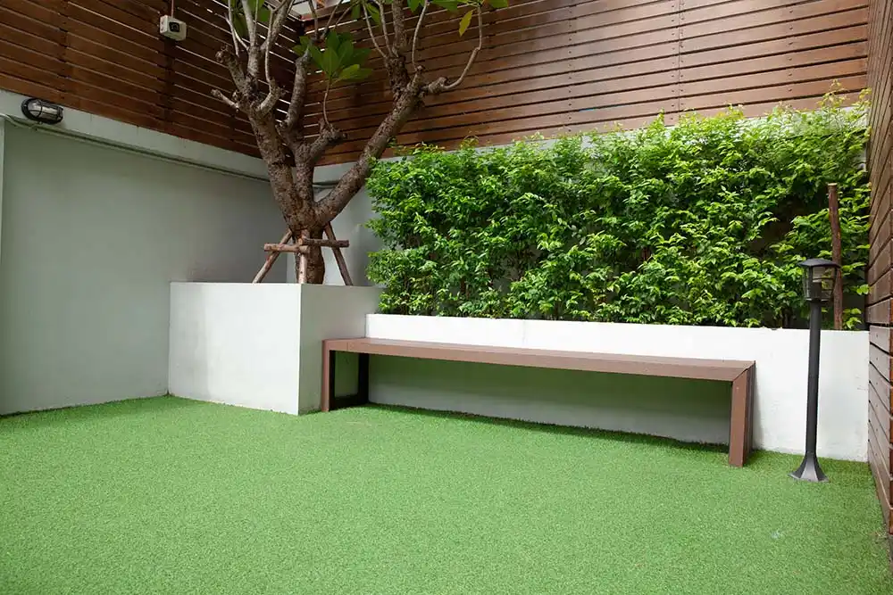 Terrasse décorée avec du gazon synthétique, créant un contraste élégant avec le mobilier contemporain