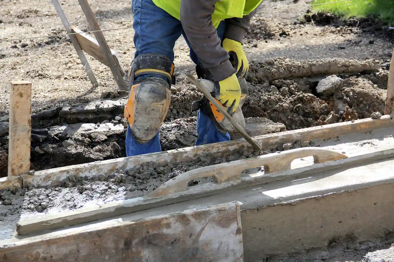 Ouvrier coulant une dalle béton sur sol en terre brute sans préparation