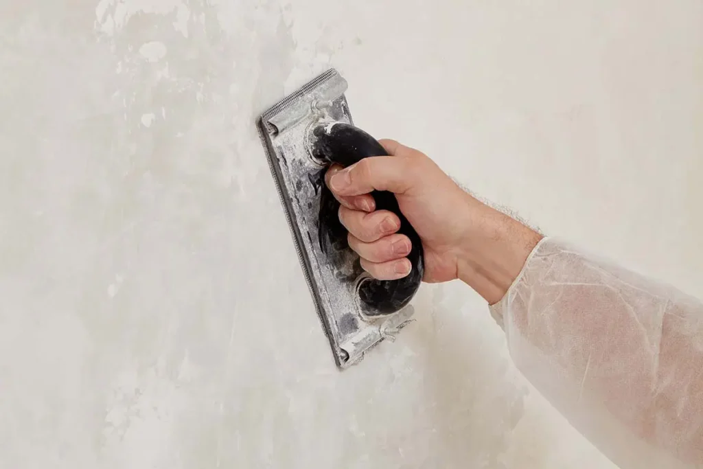 Ponçage d’un mur recouvert d’enduit à l’aide d’une cale manuelle pour obtenir une surface lisse
