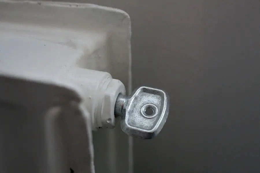 Purgeur manuel à vis sur un radiateur en fonte, utilisé pour évacuer l’air et améliorer la circulation de la chaleur