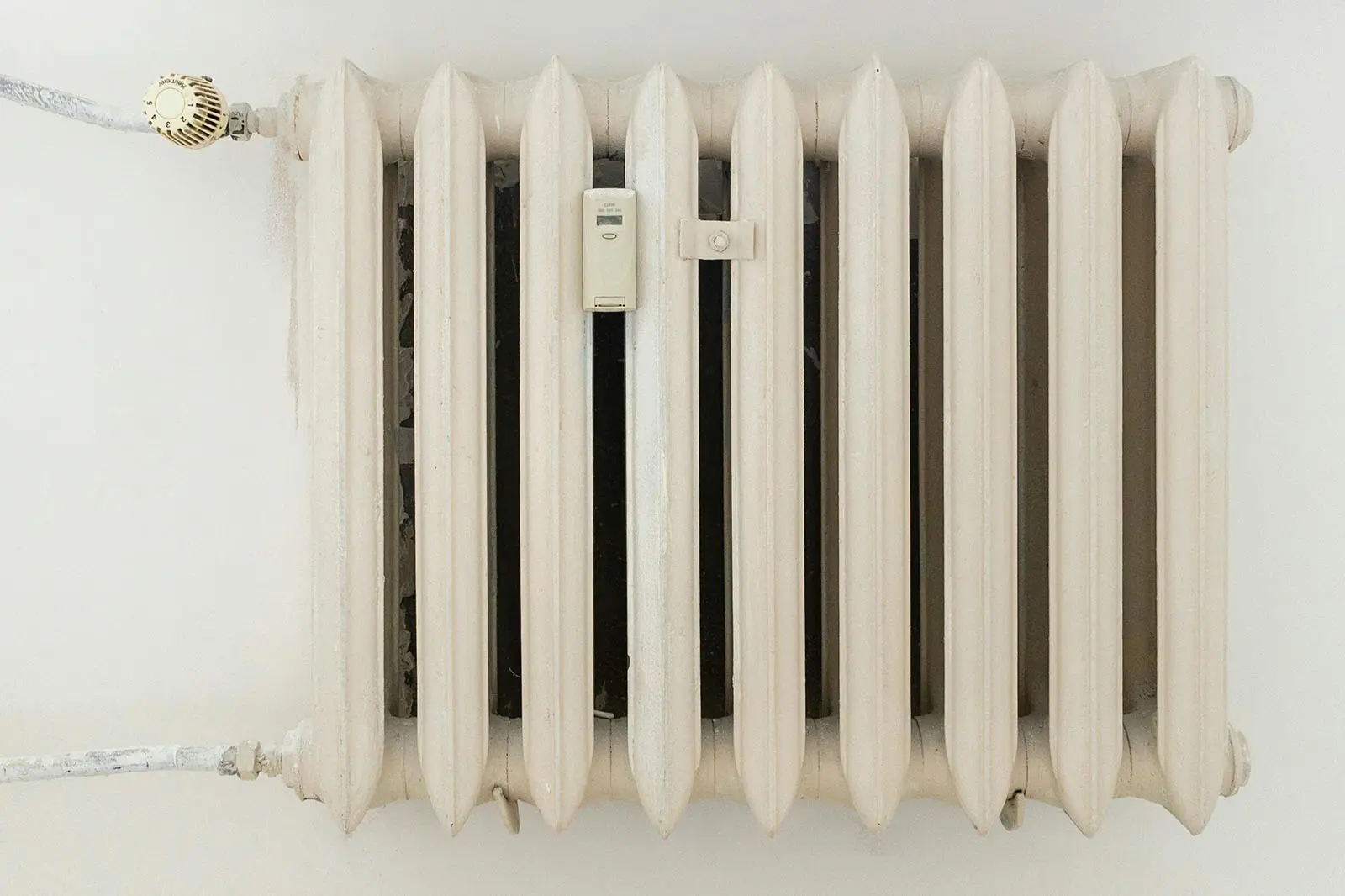 Radiateur en fonte blanc fixé au mur, idéal pour apprendre la purge et le nettoyage