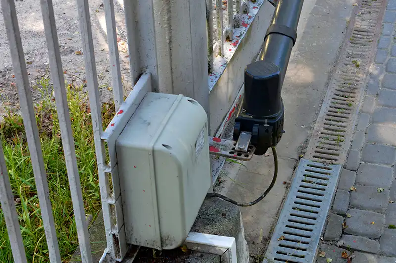 Moteur d’un portail battant électrique fixé sur un pilier, illustrant le système d’ouverture automatique et son bras articulé