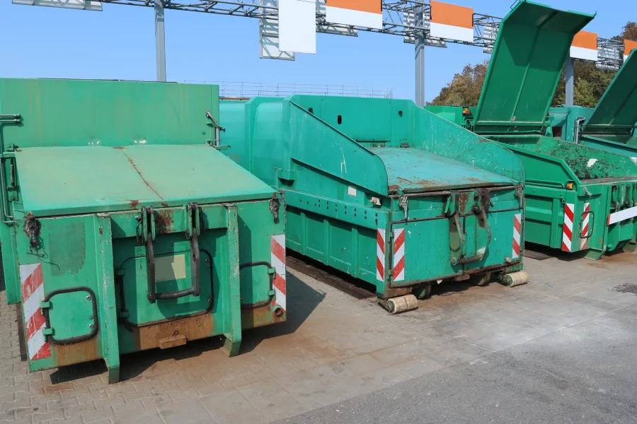 Alignement de grandes bennes vertes de tri sélectif dans un centre de collecte et déchetterie pour résidus de chantier.
