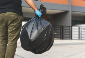 Homme portant un sac de déchets de chantier pour l'apporter en déchetterie après des travaux de rénovation.