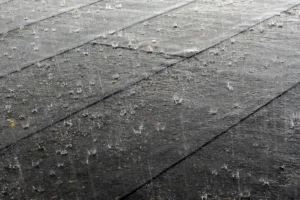 Forte pluie sur une toiture, situation pouvant provoquer une fuite de toit ou une infiltration d’eau dans la maison