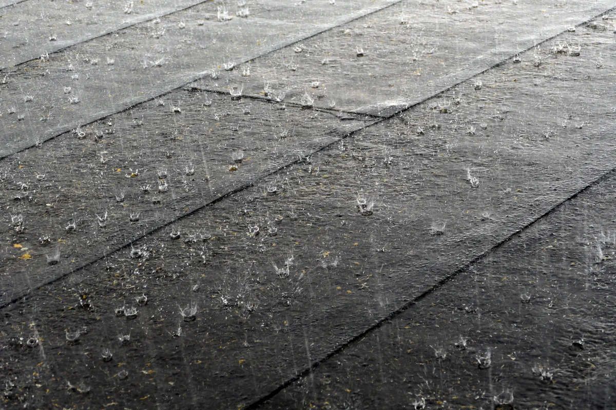 Forte pluie sur une toiture, situation pouvant provoquer une fuite de toit ou une infiltration d’eau dans la maison