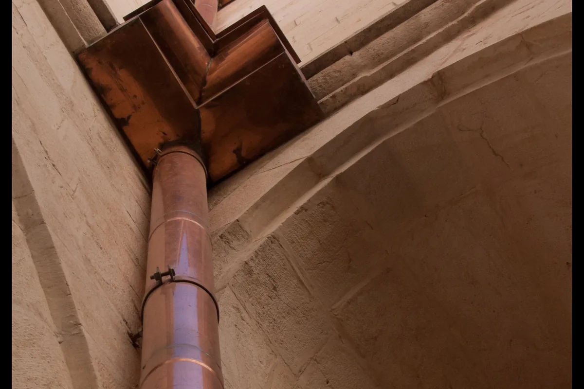 Gouttière en cuivre et descente d’eau pluviale sur une façade ancienne
