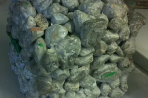 Plan rapproché de la structure poreuse du béton drainant montrant les agrégats de pierre et les vides pour le passage de l'eau, avec des marquages techniques verts.
