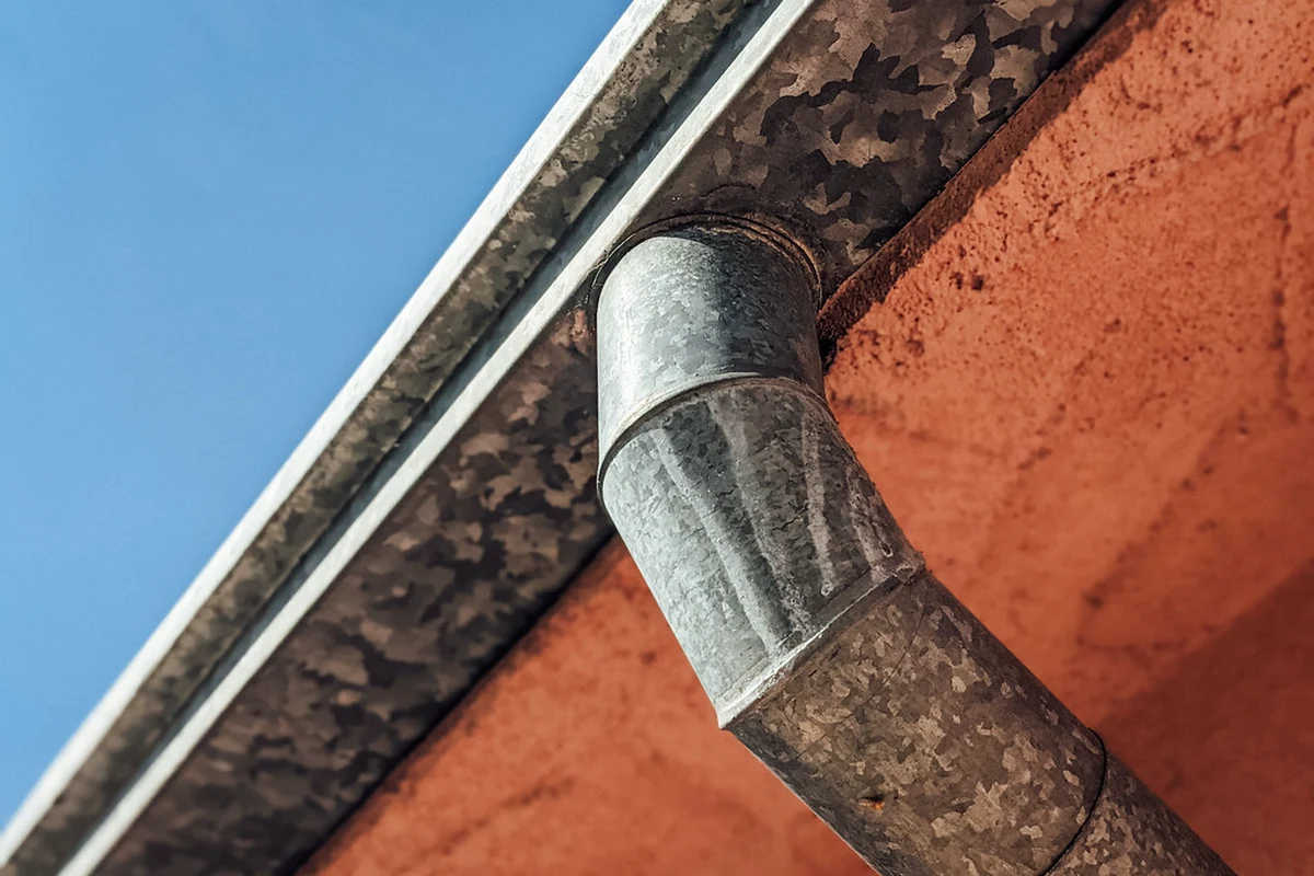 Gouttière métallique visible en bord de toit, avec descente contre la façade